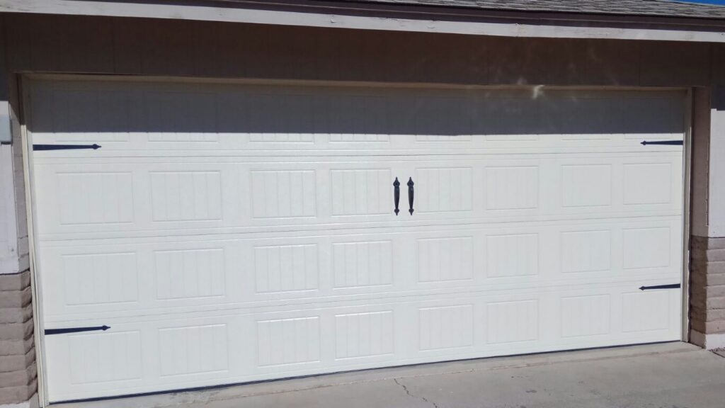 White carriage-style double garage door with black decorative hardware
