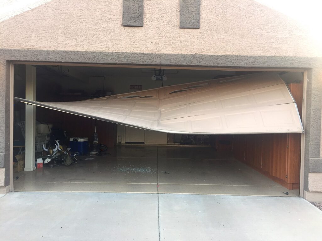 Garage door out of its tracks, hanging diagonally across the opening